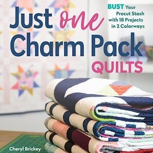May include: A stack of colorful fabric charm packs for quilting. The book cover reads "Just one Charm Pack Quilts" and "Bust Your Precut Stash with 18 Projects in 2 Colorways".