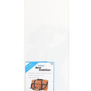 May include: A rectangular clear acrylic base stabilizer measuring 7.75 inches by 20.5 inches. The product label features the text "bannie.com Base Stabilizer" and an illustration of a patterned duffel bag, noting it is 1/8 inch thick and durable.