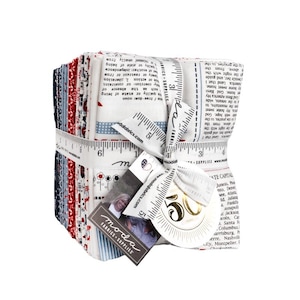 May include: A bundle of fabric squares in red, white, and blue patterns, tied with a white ribbon printed with ruler markings. The fabric bundle includes a tag with the text "moda FABRICS + SUPPLIES".