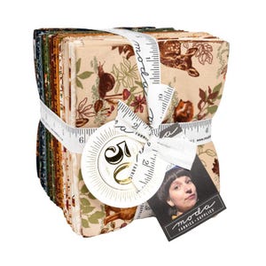 May include: A stack of fabric squares tied with a white ribbon featuring a measuring tape design. The fabric has a beige background with forest animal and plant patterns. A tag with the words "Moda Fabrics + Supplies" is attached.