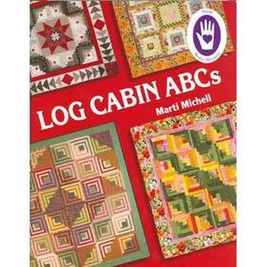 May include: Book cover featuring a colorful quilt pattern with the title "Log Cabin ABCs" by Marti Michell. The cover is red with a white hand with a heart in the center.