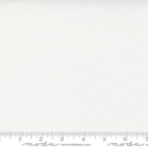 May include: A solid white fabric with a subtle texture. The fabric is shown with a ruler for scale.