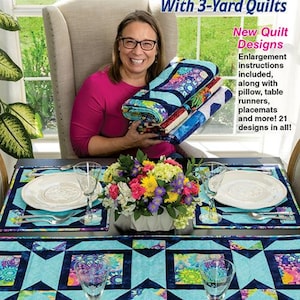 May include: A book titled "Make It Home with 3-Yard Quilts" by Fran Morgan. The cover features a woman holding a stack of colorful quilts and a table setting with a blue and black table runner and placemats.