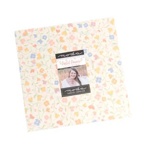 May include: A square fabric bundle with a floral pattern in pastel colors. The fabric features small flowers in shades of pink, yellow, and blue on a cream background. A label with the text "Pastel Prairie" and a woman's photo is attached.