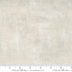 May include: A close-up of a light gray fabric with a subtle textured pattern. The fabric has a slightly distressed look, with a hint of silver shimmer.
