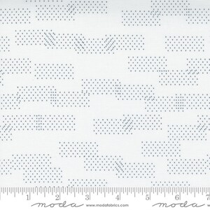 May include: White fabric with a repeating pattern of blue dotted lines and rectangles. The fabric is marked with a ruler in inches and the words "moda" and "www.modafabrics.com".