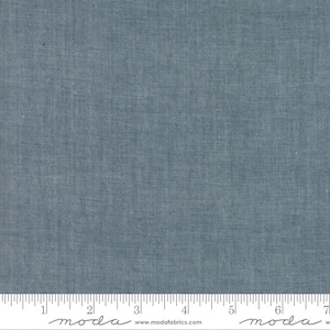 May include: A close-up of a solid blue fabric with a subtle texture. The fabric is measured with a ruler that reads "moda" and "www.modafabrics.com".
