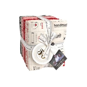 May include: A bundle of 50 fabric squares in a cream color with red and black accents. The fabric features a variety of patterns and text, including "Create", "Love", "Celebrate Every Day", and "Handmade". The bundle is tied with a white ribbon and a tag that says "moda fabrics supplies".