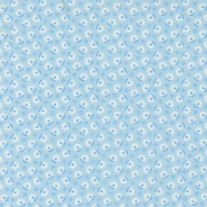 May include: Light blue fabric with a repeating pattern of white and blue floral designs. The flowers have a delicate, stylized appearance, with small petals and leaves. The background is a solid light blue color.