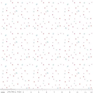 May include: White fabric with a repeating pattern of small red stars, dots, and light blue floral-like shapes. The pattern is evenly distributed across the surface. The image includes a ruler with inches.