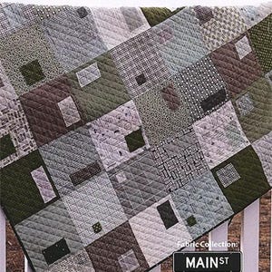 May include: A patchwork quilt with a variety of green, gray, and brown patterned squares. The quilt is 64" x 64" and features the text "MIXED BAG" and "MAIN ST Sweetwater".