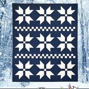 May include: A navy blue quilt featuring a repeating white star pattern and two horizontal rows of white checkerboard squares. The text SWEATER WEATHER is printed at the top, and the text Running Doe QUILTS For Villa Rosa Designs is at the bottom.