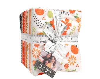May include: A stack of folded fabric squares tied with a white measuring tape featuring the text moda fabrics and supplies. The fabric displays a pattern of orange pumpkins, green leaves, and orange flowers on a white background with a tag.