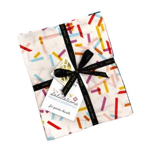 May include: A bundle of fabric squares with a colorful confetti pattern in red, yellow, blue, and purple on a white background. The bundle is tied with a black ribbon and a tag that reads "Salutations".