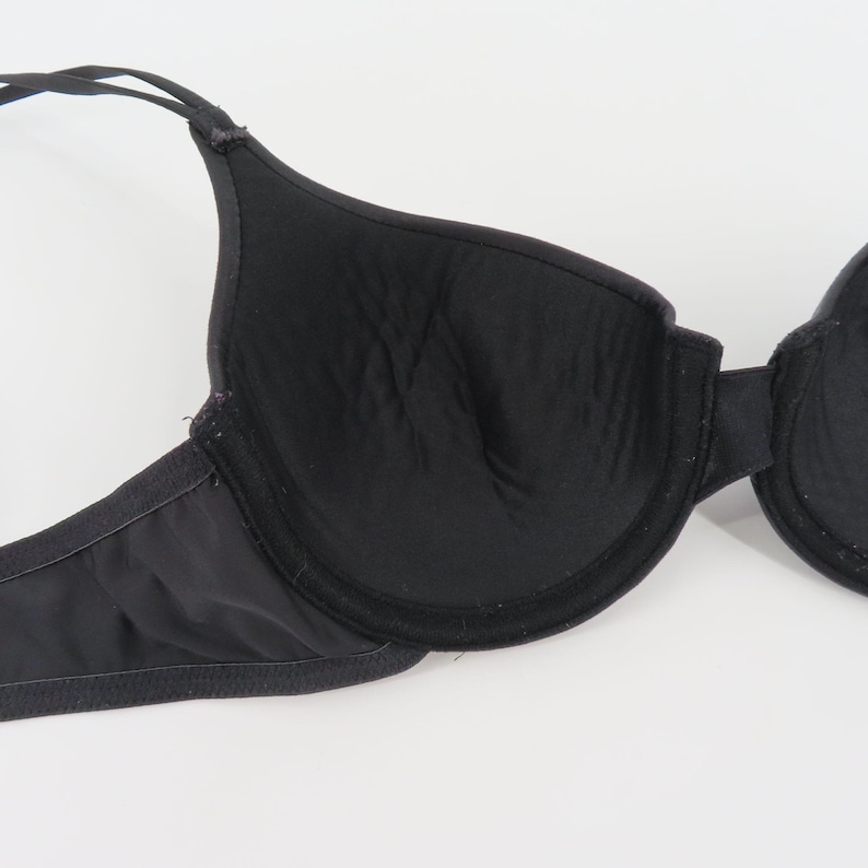 Op de afbeelding: Zwarte beha met verstelbare bandjes. De beha heeft voorgevormde cups en beugelondersteuning. De stof lijkt glad en licht glanzend. Deze beha is ontworpen voor dagelijks gebruik en biedt ondersteuning en bedekking.