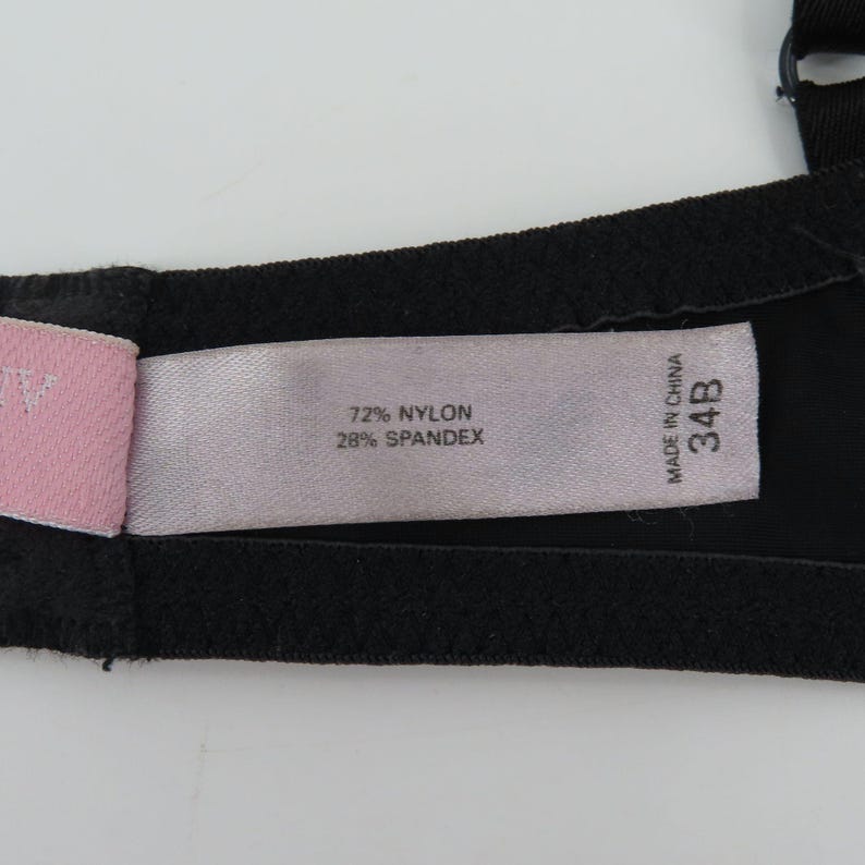 Op de afbeelding: Zwarte beha met een label met de tekst "72% Nylon 28% Spandex" en "Made in China 34B". De beha is gemaakt van een zachte, rekbare stof.