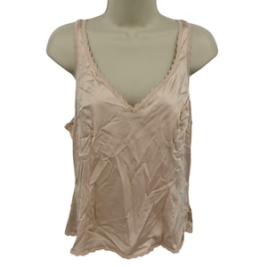May include: A light peach-colored camisole with a V-neckline and delicate lace trim along the neckline and straps. The sleeveless top is made of a silky, smooth fabric and is displayed on a mannequin.