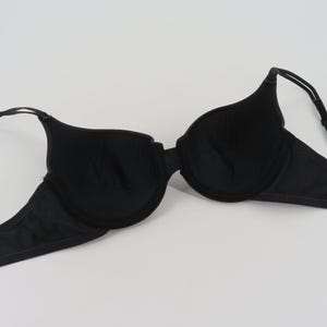 Op de afbeelding: Een zwarte beha met beugel, met voorgevormde cups en verstelbare bandjes. De beha is gemaakt van een gladde, effen zwarte stof en is ontworpen voor dagelijks gebruik. De beha ligt plat op een witte achtergrond.