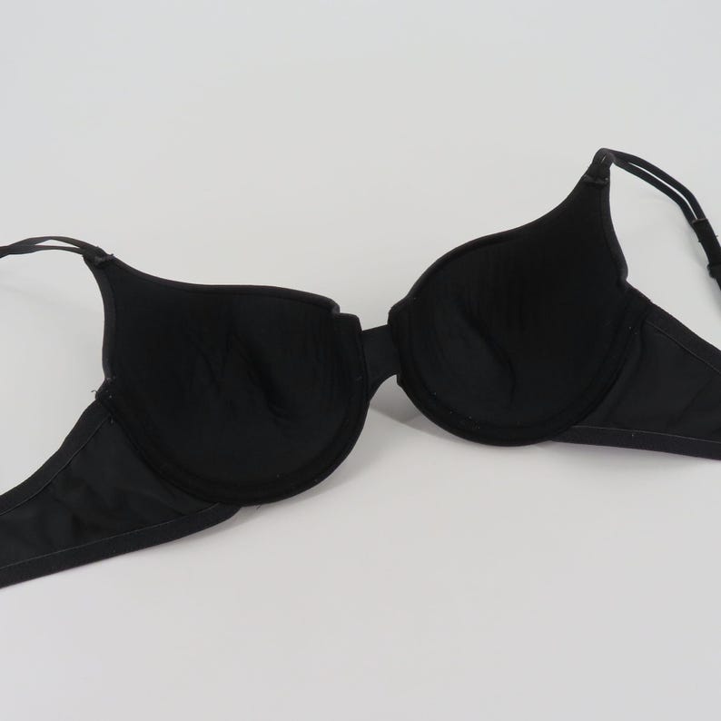 Op de afbeelding: Een zwarte beha met beugel, met voorgevormde cups en verstelbare bandjes. De beha is gemaakt van een gladde, effen zwarte stof en is ontworpen voor dagelijks gebruik. De beha ligt plat op een witte achtergrond.