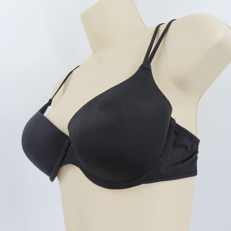 Op de afbeelding: Zwarte beha met dunne, verstelbare bandjes, getoond op een mannequin. Het ontwerp is glad en naadloos. De beha heeft een klassieke vorm en is gemaakt van een effen, ondoorzichtig materiaal. Biedt ondersteuning en comfort.