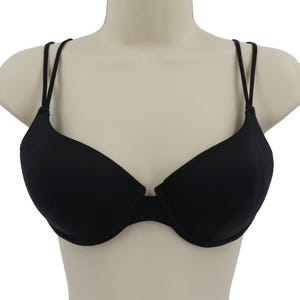 Op de afbeelding: Een zwarte beha met dunne, verstelbare bandjes. De beha heeft een klassiek ontwerp met voorgevormde cups en een lage middenvoor. De beha wordt op een mannequin getoond.