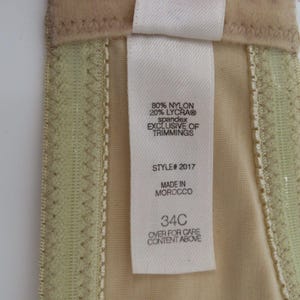May include: Close-up of a beige bra with a tag. The tag reads "80% NYLON 20% LYCRA&reg; spandex EXCLUSIVE OF TRIMMINGS STYLE# 2017 MADE IN MOROCCO 34C OVER FOR CARE CONTENT ABOVE."
