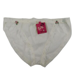 May include: White bikini underwear with lace trim and small floral accents. A pink tag with the text "tutu" is attached. The underwear has a classic cut and appears to be made of a lightweight fabric.