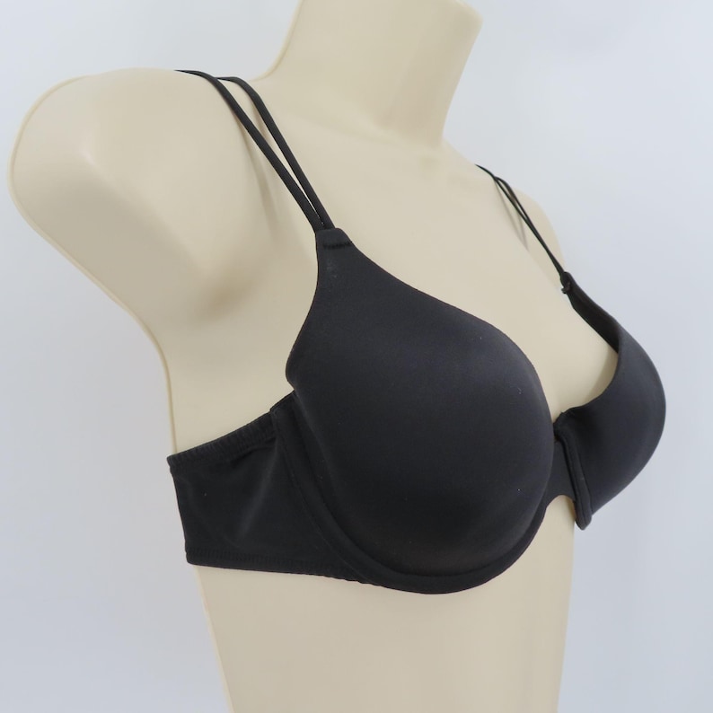 Op de afbeelding: Een zwarte bh met dunne, verstelbare bandjes. De bh heeft een glad, naadloos ontwerp en beugelondersteuning. De bh wordt op een mannequin gepresenteerd tegen een effen witte achtergrond.