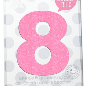 Könnte beinhalten: Rosa Bügelbild der Zahl Acht mit glitzernder Textur. Die Zahl befindet sich auf einem weißen Hintergrund mit grauen Punkten. Der Text "Bügel-Bild" befindet sich in einer Sprechblase über der Zahl. Der Text "Bitte die Bügelanleitung auf der Karteninnenseite beachten!" befindet sich unter der Zahl. Der Text "Gedruckt auf 100% Altpapier. MIMMIS TRAKTOR®" befindet sich am unteren Rand des Bildes.