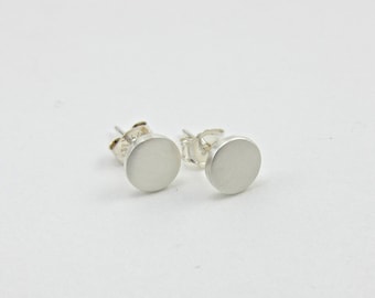 Op de afbeelding: Een paar zilveren oorbel studs met ronde, gladde, platte voorkanten.