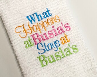 May include: White kitchen towel with colorful embroidered text that reads "What Happens at Busia's Stays at Busia's".