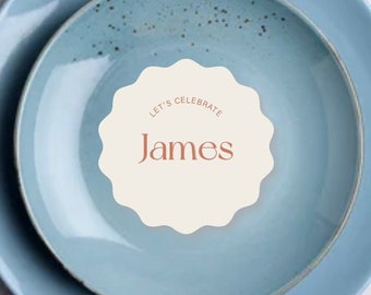 Könnte beinhalten: Ein blaues und weißes Gedeck mit einer weißen Platzkarte, auf der "Let's Celebrate James" steht.