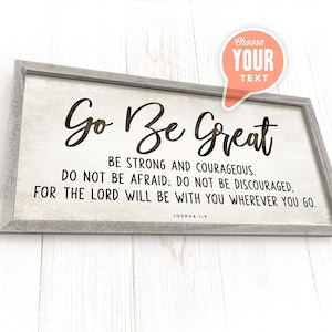 May include: A framed wood sign with a white background and black text that reads "Go Be Great" with a bible verse from Joshua 1:9. The sign is on a white wood background.