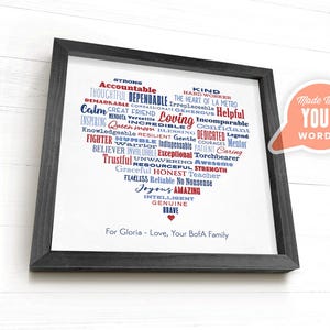 May include: Framed print with a heart-shaped design filled with positive words in red and blue. The words describe qualities like "Strong," "Loving," and "Amazing." The print is in a black frame and includes the text "Made With YOUR WORDS."