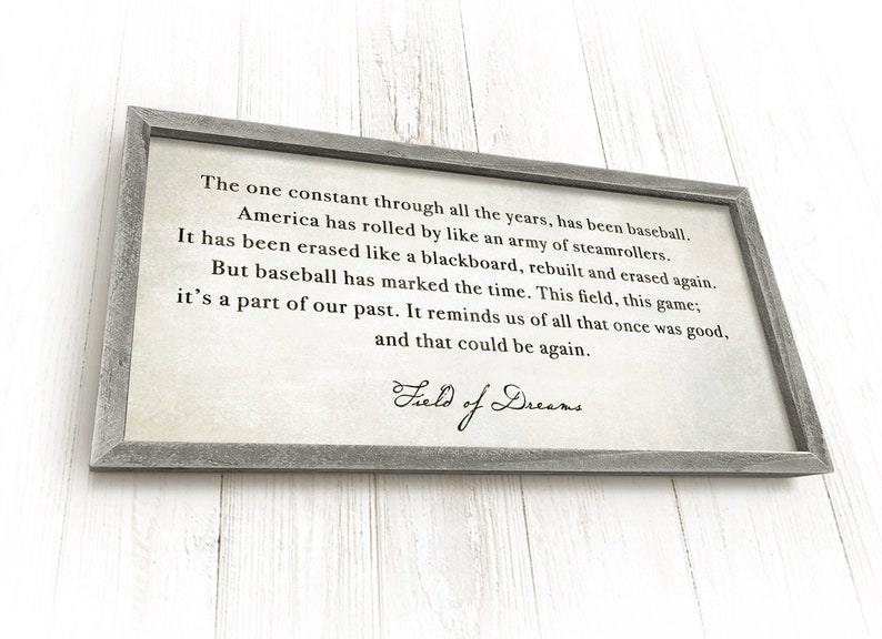 May include: A framed print with a quote about baseball and the passage of time. The quote reads: "The one constant through all the years, has been baseball. America has rolled by like an army of steamrollers. It has been erased like a blackboard, rebuilt and erased again. But baseball has marked the time. This field, this game; it's a part of our past. It reminds us of all that once was good, and that could be again." The print is signed "Field of Dreams".