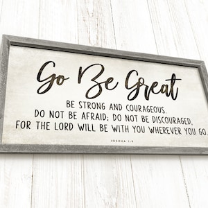 May include: A framed wood sign with a white background and black text. The sign reads "Go Be Great" and includes a bible verse from Joshua 1:9, "Be strong and courageous. Do not be afraid: Do not be discouraged, for the Lord will be with you wherever you go."