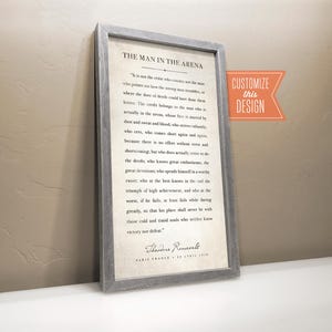 May include: A rectangular framed wall art piece featuring a weathered gray wooden frame and a cream-colored background. The text displays the full Man in the Arena speech by Theodore Roosevelt, including the date and location at the bottom.