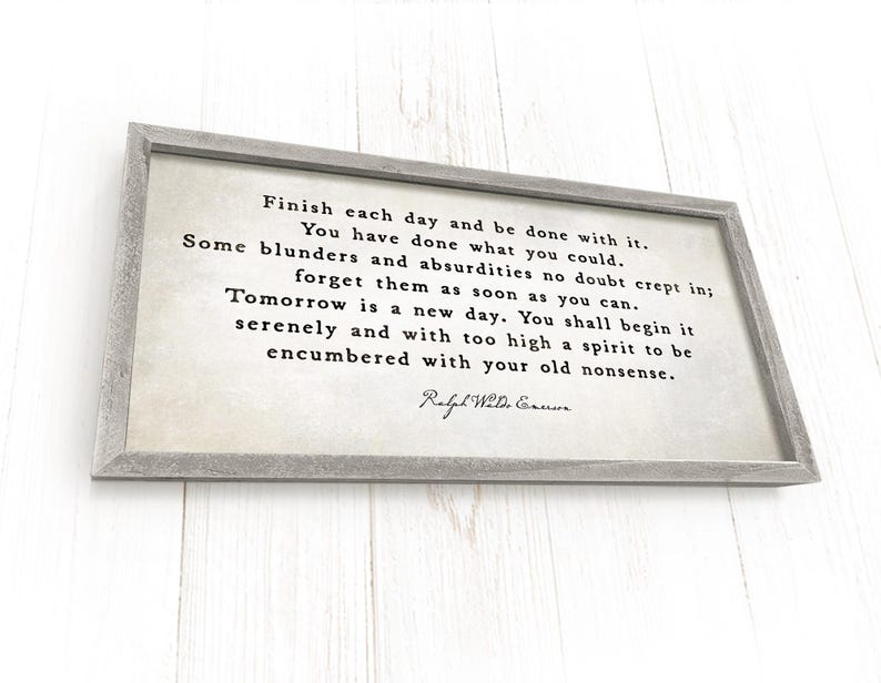 May include: A rectangular wooden sign with a gray frame. The sign features a quote in black text on a cream-colored background. The quote is attributed to Ralph Waldo Emerson.