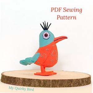 May include: PDF sewing pattern for a quirky, orange and turquoise bird with a large eye and a black crest. The bird is standing on a wooden surface. The text "My Quirky Bird" is visible at the bottom of the image.