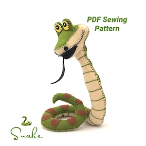 Puede incluir: Un patrón de costura PDF para una serpiente de fieltro verde con manchas marrones. La serpiente tiene un cuerpo largo y delgado con una cabeza grande y una amplia sonrisa con dientes. Los ojos de la serpiente son grandes y amarillos, y su lengua es larga y negra. El patrón incluye instrucciones para hacer el cuerpo, la cabeza y la lengua de la serpiente.