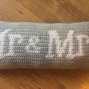 May include: A gray crocheted pillow with the word "Home" embroidered in white.
