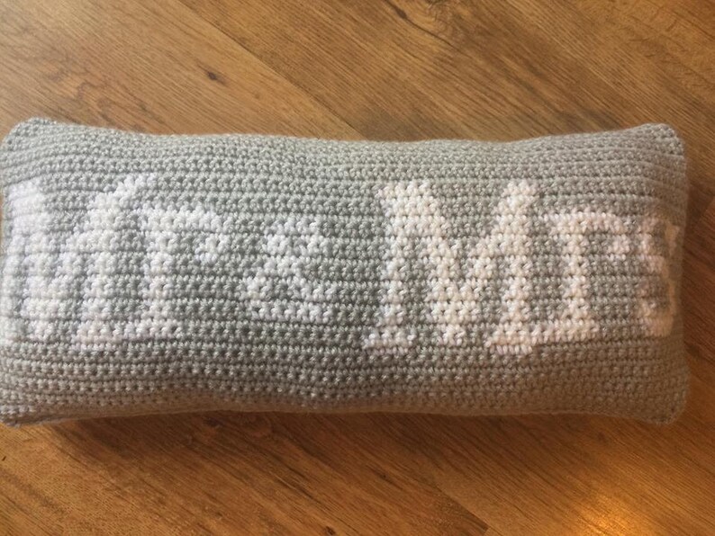 May include: A gray crocheted pillow with the word "Home" embroidered in white.