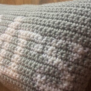 May include: A gray and white crocheted pillow with a geometric pattern.