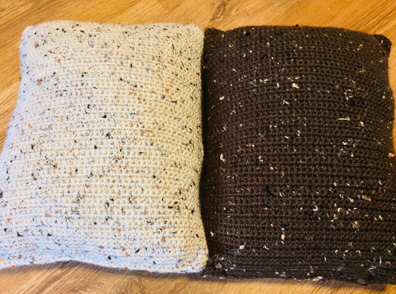 May include: Two crocheted throw pillows, one white with brown flecks and one brown with white flecks.