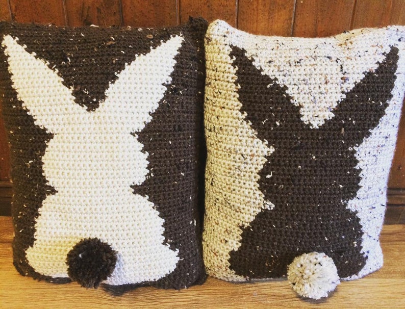 May include: Two crocheted pillow covers with a bunny silhouette design. One pillow cover is white with a brown bunny, and the other is brown with a white bunny.