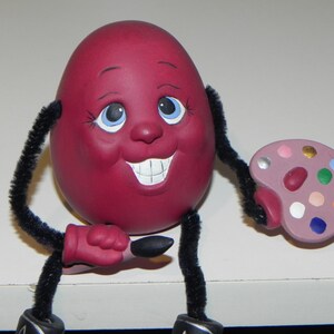 Hand Painted Ceramic; Burgundy egg with hands, legs,boots, painting pallet, brush