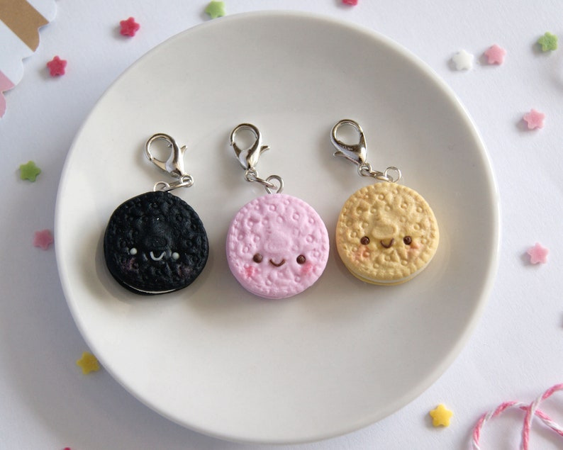 Op de afbeelding: Drie bedelarmen in de vorm van koekjes met blije gezichtjes. De koekjes zijn zwart, roze en geel.