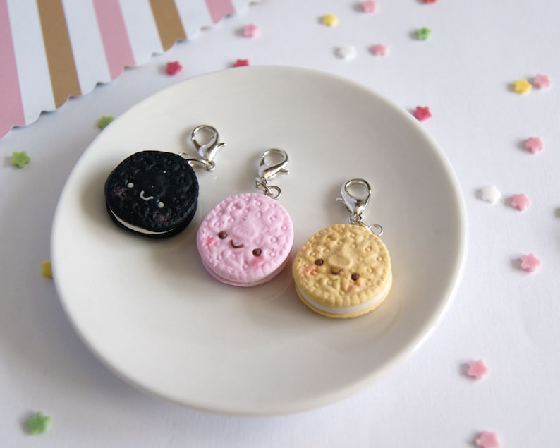 Op de afbeelding: Drie bedelarmen in de vorm van koekjes met schattige gezichtjes. De koekjes zijn zwart-wit, roze-wit en geel-wit.