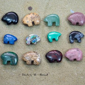 May include: A collection of twelve small bear-shaped stone carvings in various colors including black, tan, green, blue, pink, and iridescent patterns, arranged in three rows next to a silver United States dime for scale, with the text Batch 8 Small.