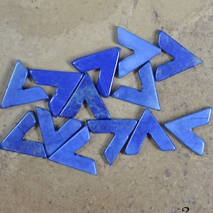 May include: A collection of blue Lapis Howlite arrow-shaped stones. The stones are arranged on a brown surface. The text "#2 Lapis Howlite" is visible in the lower right corner.